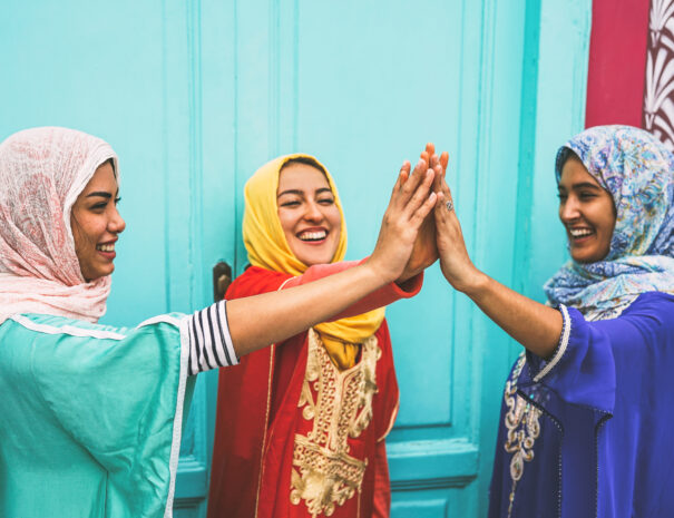 Happy Arabian women stacking hands together outdoor - Young Muslim women having fun and in the university - Concept of empowering, people, religion and team work